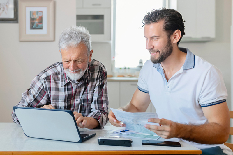 A son helping his dad on his laptop